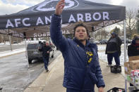 Michigan running back Blake Corum motions to a fellow volunteer during a turkey dinner giveaway event outside a school in Ypsilanti, Mich., on Sunday, Nov. 20, 2022. Corum took part in the charitable effort a day after hurting his knee and less than a week before his third-ranked Wolverines play No. 2 Ohio State. (AP Photo/Mike Householder)