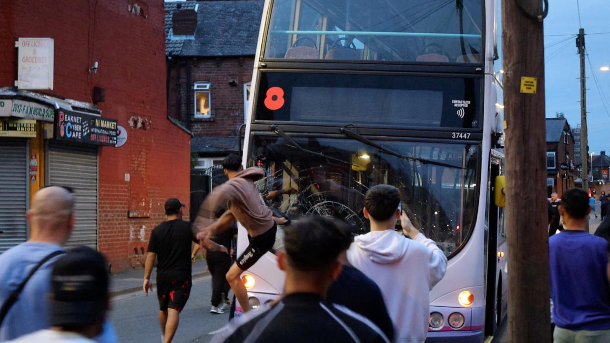 A man kicks a bus during unrest in Harehills, Leeds, Britain, July 18, 2024 in this still image obtained from social media video.  ?@robin_singh? via Instagram/via REUTERS  THIS IMAGE HAS BEEN SUPPLIED BY A THIRD PARTY. MANDATORY CREDIT.