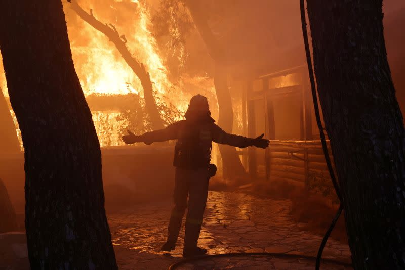 FILE PHOTO: A firefighter reacts as a wildfire burns at Varympompi suburb north of Athens, Greece, August 3, 2021