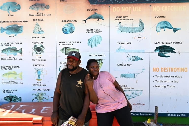 Des habitants devant une affiche répertoriant les espèces protégées à Honiara, dans les îles Salomon, le 21 avril 2024 (Saeed KHAN)