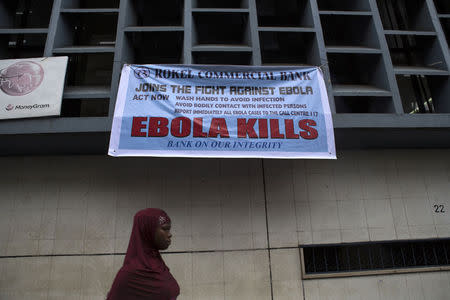 A woman passes a sign posted in an awareness campaign against the spread of Ebola in Freetown, Sierra Leone September 18, 2014 in a handout photo provided by UNICEF. REUTERS/Bindra/UNICEF/handout via Reuters