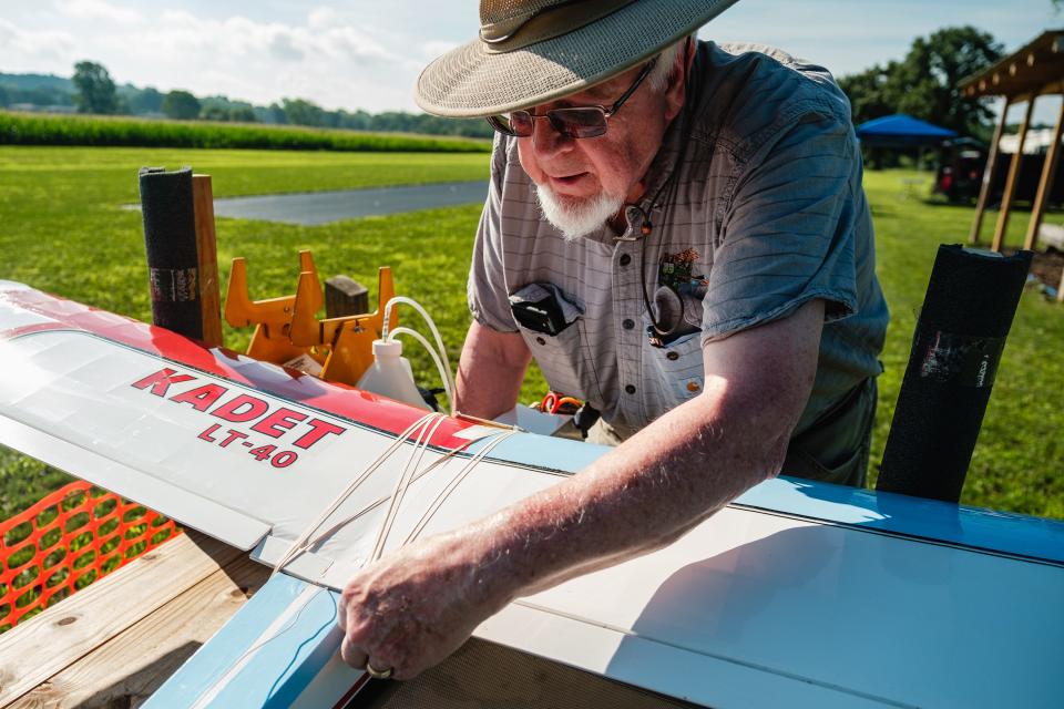 Robert Draman, current OldTown Valley Flyer's Club president, affixes rubber bands to one of his airplanes to hold the wing in place as he gets ready for the annual Academy of Model Aeronautics National Model Aviation Day, Saturday, Aug. 12 on a private field in Lawrence Township.