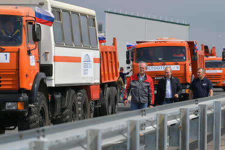 Russian President Vladimir Putin (C), businessman Arkady Rotenberg (R) and construction manager Alexander Ostrovsky walk before a ceremony opening a bridge, which was constructed to connect the Russian mainland with the Crimean Peninsula, near the Taman Peninsula in Krasnodar Region, Russia May 15, 2018. Sputnik/Alexei Druzhinin/Kremlin via REUTERS