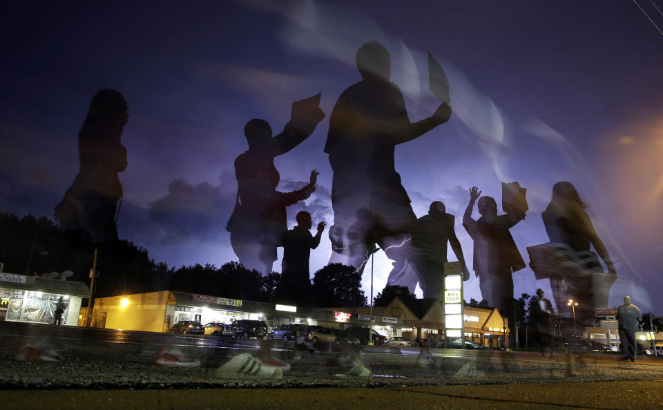 FILE - Protesters march in the street as lightning flashes in the distance in Ferguson, Mo., Aug. 20, 2014, following the shooting of Michael Brown, an unarmed Black teen, in the St. Louis suburb on Aug. 9. On Tuesday, Jan. 3, 2024, a St. Louis-based public interest law firm announced that the city of Florissant, Mo., will pay nearly $3 million to settle a so-called debtor's prison lawsuit that accused Florissant and six other St. Louis suburbs of violating the constitutional rights of residents by jailing them and forcing them to pay fines and fees amounting to millions of dollars. Florissant was among several St. Louis County cities whose policing and court practices fell under scrutiny after the fatal police shooting of Brown. (AP Photo/Jeff Roberson, File)