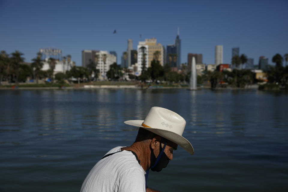 A street vendor with a face mask pushes his cart during the coronavirus pandemic in the Westlake neighborhood of Los Angeles, Thursday, May 21, 2020. A study released Wednesday by the University of California, Los Angeles, found 40 percent of blacks and Latinos live in neighborhoods with the perfect mix of ingredients for exposure to the virus because they are less likely to be able to abide by stay-at-home orders and keep their distance from others. (AP Photo/Jae C. Hong)