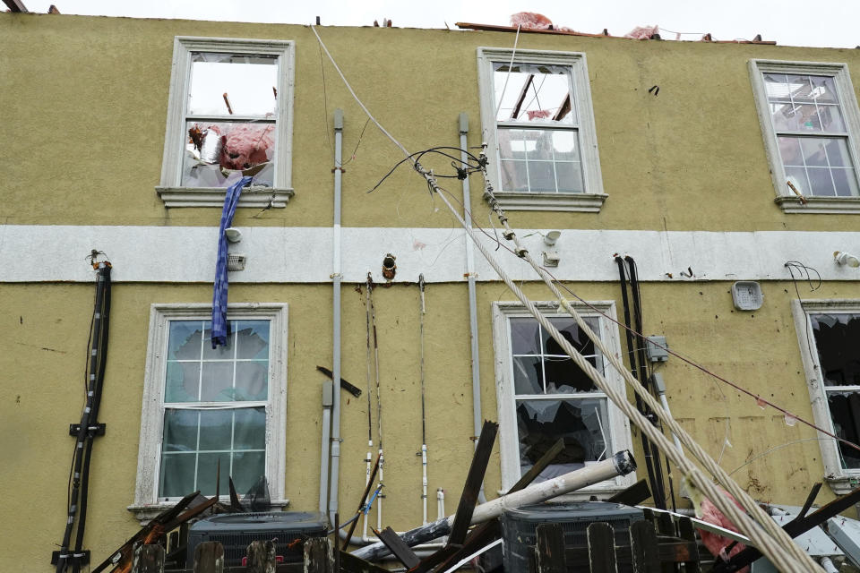 Broken glass and other debris hang from the back of an apartment complex after a tornado removed its roof Saturday, May 13, 2023, in Laguna Heights, Texas. At least one person was killed when a tornado struck an unincorporated community on the Gulf coast near the southern tip of Texas, damaging dozens of homes and knocking down power lines early Saturday, authorities said. (Denise Cathey/The Brownsville Herald via AP)