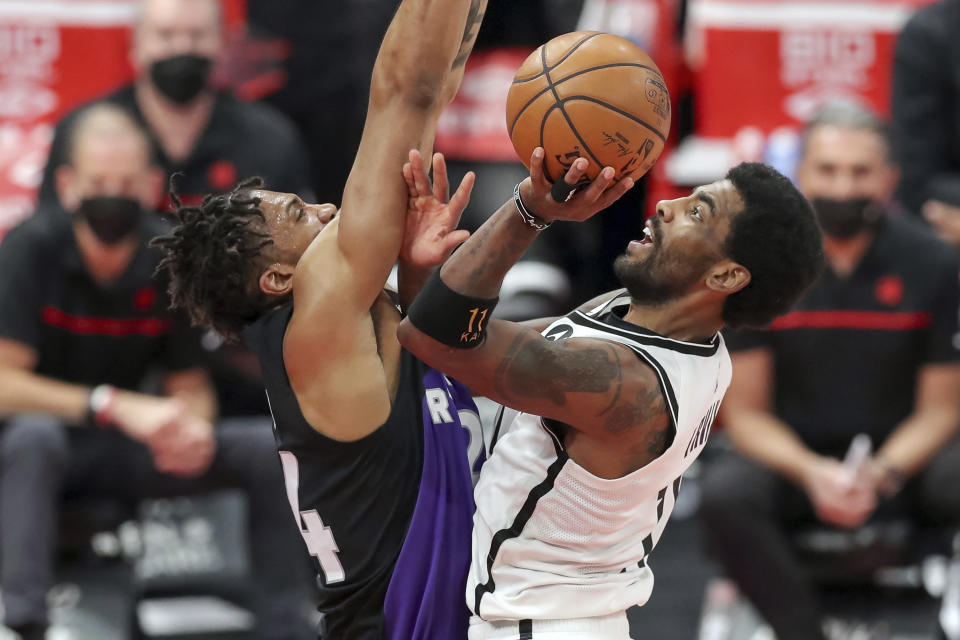 Brooklyn Nets' Kyrie Irving, right, goes up for a shot against the defense of Toronto Raptors' Khem Birch during the second half of an NBA basketball game Wednesday, April 21, 2021, in Tampa, Fla. (AP Photo/Mike Carlson)