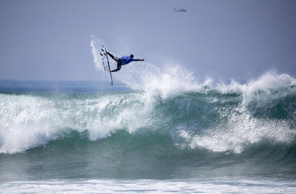 Italo Ferreira soars high over a big wave while competing against countryman Filipe Toledo