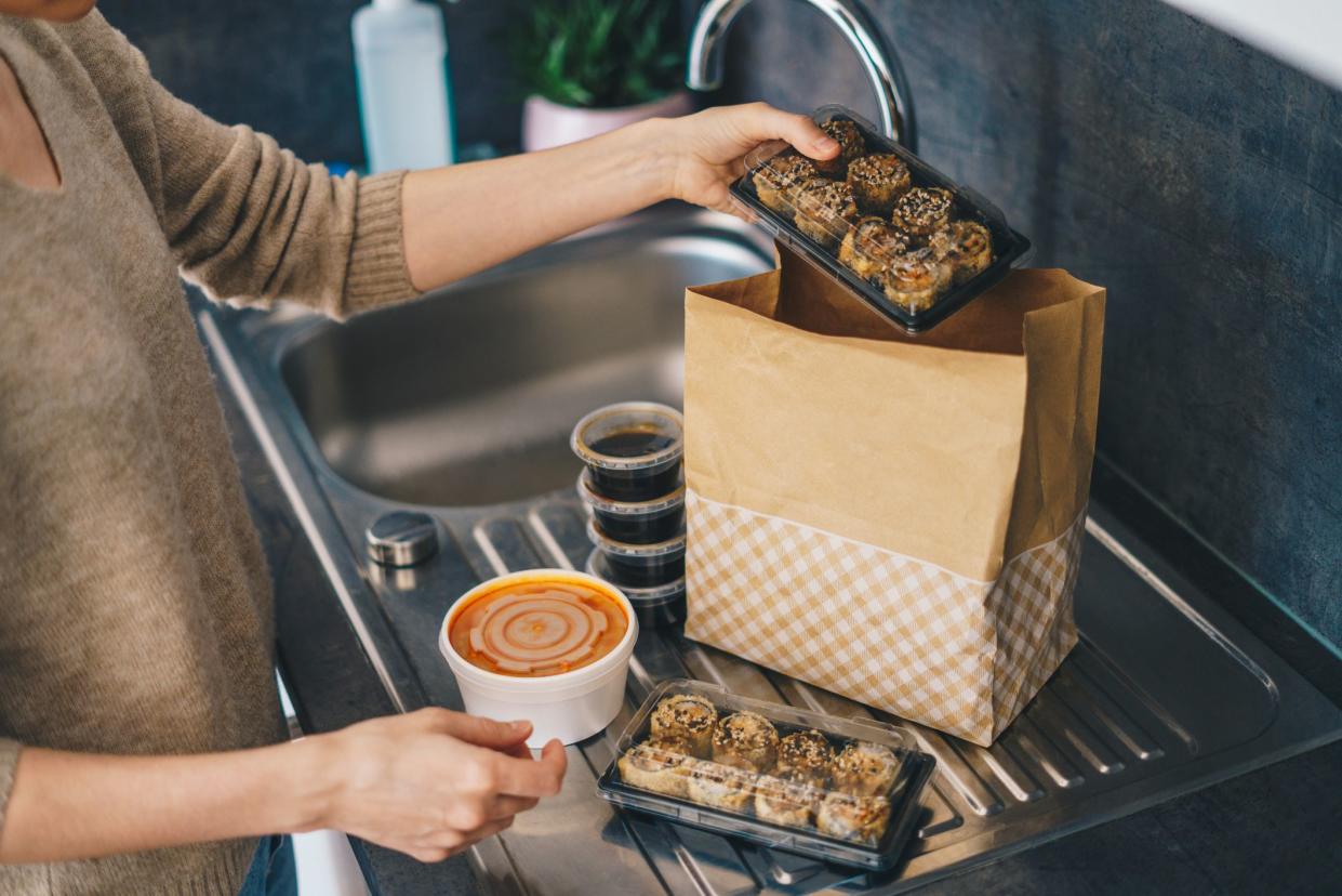 Woman carefully unpacking take out food boxes near the kitchen sink