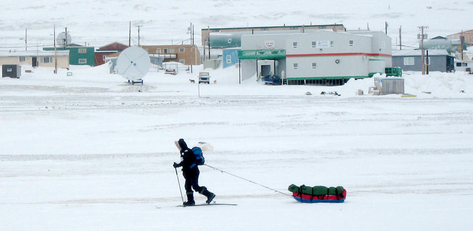 A man on skis travels across frozen sea past the Canadian Arctic settlement of Resolute Bay, Nunavut April 9, 2006. The settlement was founded in 1953 when the Canadian government dumped 14 aboriginal Inuit people on the frozen, stony beach. The Inuit say Ottawa tricked them into moving and some want an apology for the way they were treated. Picture taken April 9, 2006. To match feature CANADA RELOCATION REUTERS/David Ljunggren