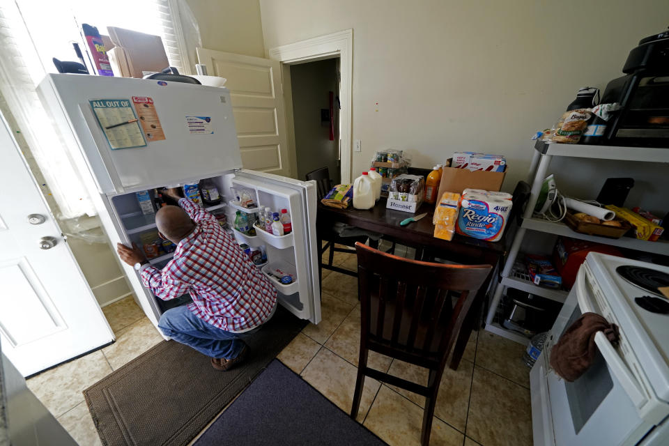 Norman Butler unboxes food that he received at a food distribution point, in his apartment, after waiting in line overnight, in New Orleans, Thursday, Nov. 19, 2020. Before the pandemic, Butler, 53, flourished in the tourism-dominated city, working as an airport shuttle and limousine driver, a valet and hotel doorman. Since March when the normally bustling streets turned silent, the only work he’s had has been as an Uber driver. (AP Photo/Gerald Herbert)