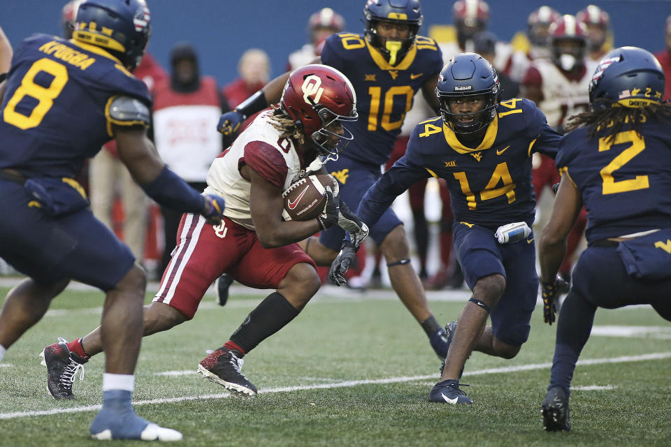 Oklahoma running back Eric Gray (0) is defended by West Virginia safety Malachi Ruffin (14) during the second half of an NCAA college football game in Morgantown, W.Va., Saturday, Nov. 12, 2022. (AP Photo/Kathleen Batten)