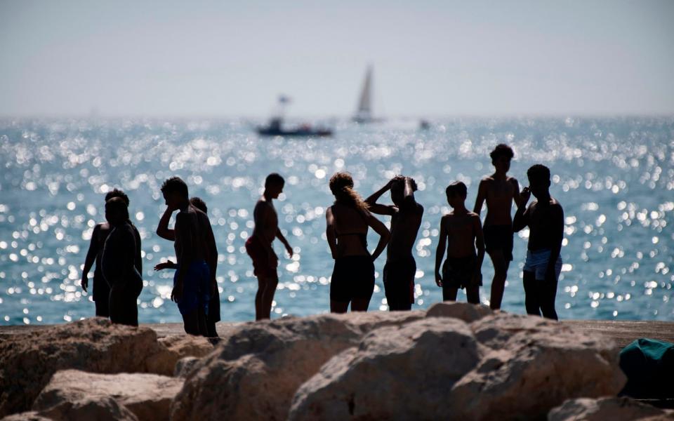 Youth gather at the "Huveaune" rocky beach at the beginning of a heatwave in Marseille, southern France - CLEMENT MAHOUDEAU/AFP