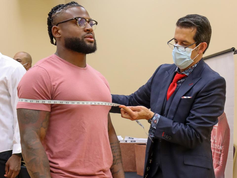 A Men's Wearhouse tailor (right) takes the measurements of a Jackson State player.