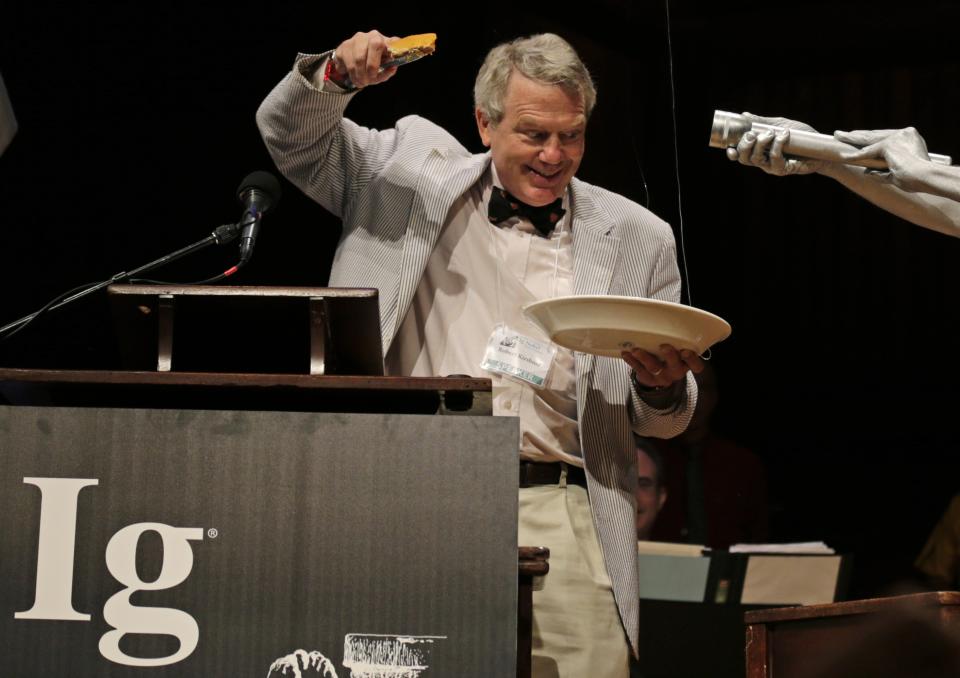 CORRECTS TO REMOVE REFERENCE TO KIRSHER WINNING 2011 NOBEL PRIZE FOR PHYSICS, ADDS HIS CURRENT TITLE - Harvard University Clowes Professor of Science Robert Kirshner holds up a piece of pie while explaining a pie chart about the universe, shortly before eating it, during a performance at the Ig Nobel Prize ceremony at Harvard University, in Cambridge, Mass., Thursday, Sept. 20, 2012. The Ig Nobel prize is an award handed out by the Annals of Improbable Research magazine for silly sounding scientific discoveries that often have surprisingly practical applications. (AP Photo/Charles Krupa)