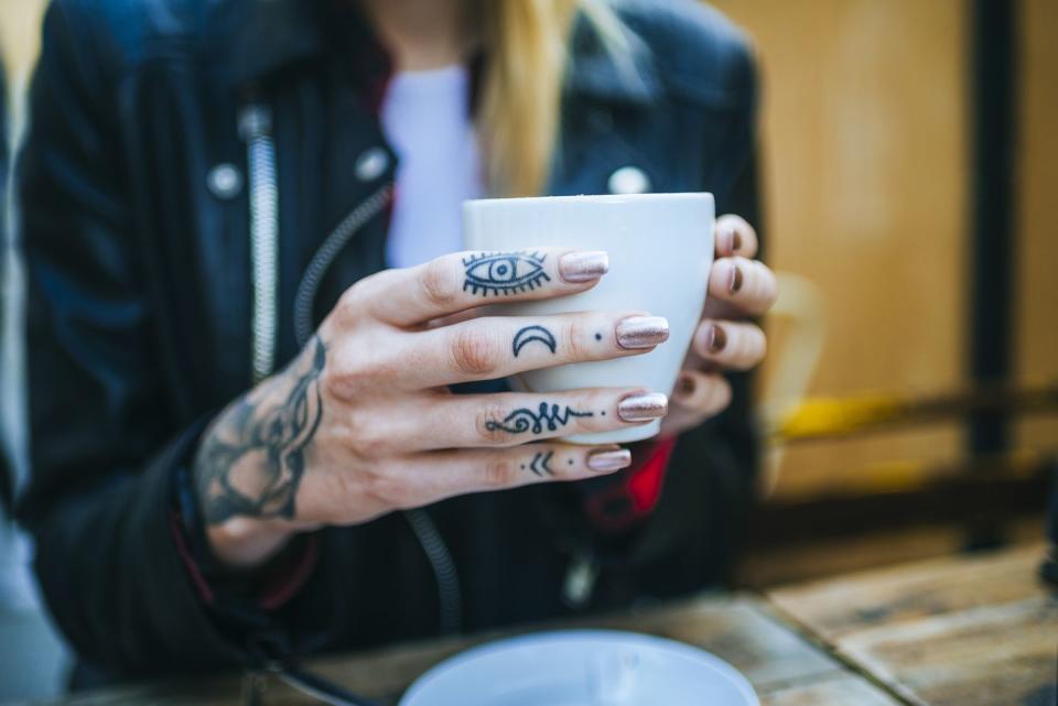 close up of tattooed woman&#39;s hand with coffee