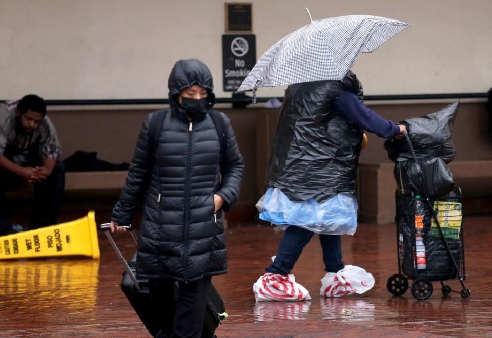 One person carrying an umbrella has covered their feet in plastic Target bags