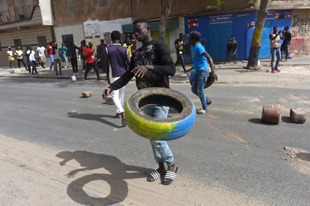 People clear a street blocked by demonstrators during a protest in Dakar