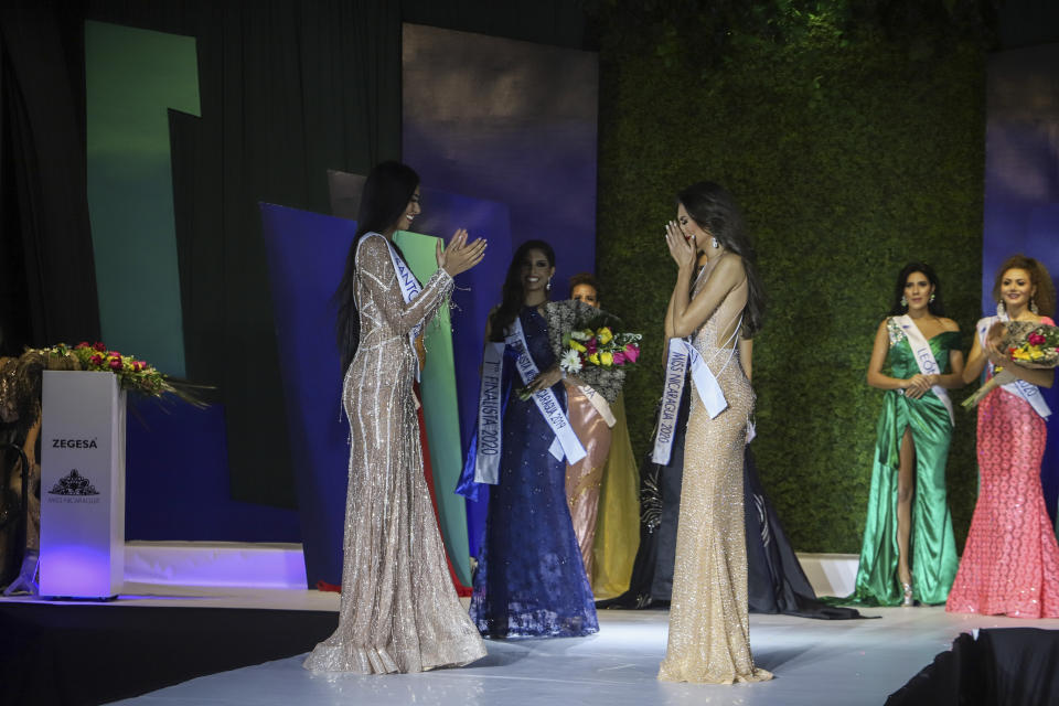 Ana Marcelo, an agroindustrial engineer from the city of Esteli, center right, reacts after being chosen Miss Nicaragua, in Managua, Nicaragua, Saturday, Aug. 8, 2020. Marcelo was crowned in front of a limited audience (two people per contestant spaced safely) plus a production crew of 85. The masks were off the contestants, but the judges wore them and were spaced at a safe distance. (AP Photo/Alfredo Zuniga)