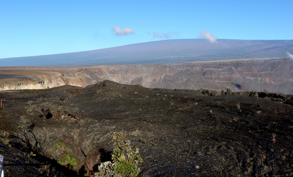 FILE - Hawaii's Mauna Loa volcano, background, towers over the summit crater of Kilauea volcano in Hawaii Volcanoes National Park on the Big Island on April 25, 2019. A magnitude 5.7 earthquake struck the world's largest active volcano Friday, Feb. 9, 2024, Mauna Loa on the Big Island of Hawaii, knocking items off shelves in nearby towns but not immediately prompting reports of serious damage. (AP Photo/Caleb Jones, File)