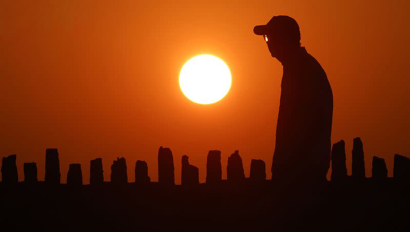 As exceptionally warm weather moves into the upper Midwest, a pedestrian walks at sunset, in Oconomowoc, Wis., on Tuesday, Aug. 22, 2023.