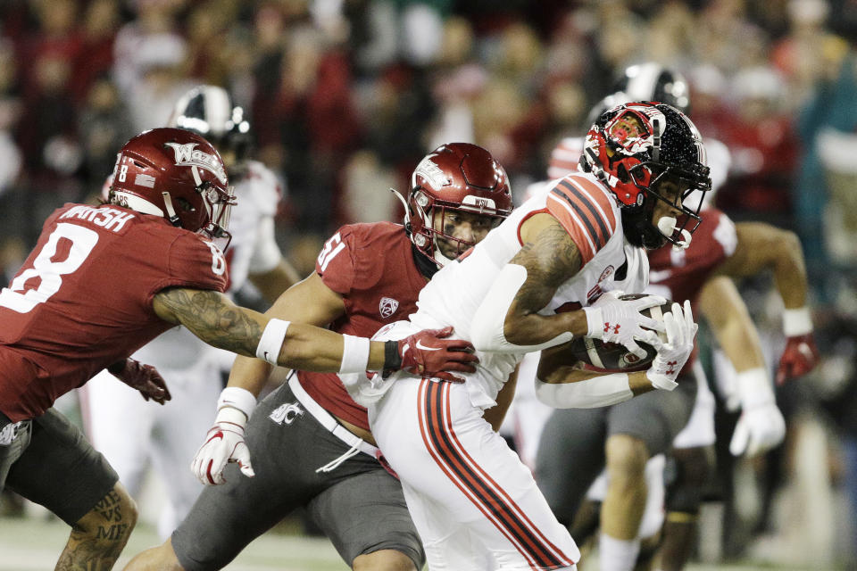 Utah wide receiver Solomon Enis, right, carries the ball while pressured by Washington State defensive back Armani Marsh, left, and linebacker Francisco Mauigoa during the first half of an NCAA college football game, Thursday, Oct. 27, 2022, in Pullman, Wash. (AP Photo/Young Kwak)