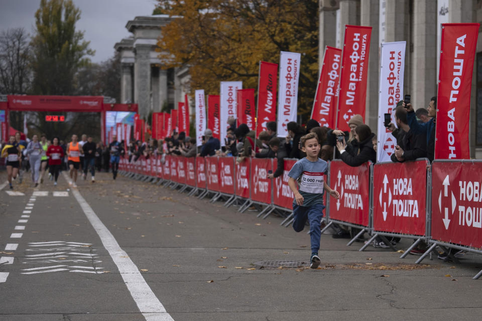 A boy runs in front of other participates of a one-kilometer race in Kyiv, Ukraine, Sunday, Oct. 29, 2023. Around two thousand Ukrainians registered for the event, called 'The World's Longest Marathon', with the dual purpose of honoring the country's military and raising funds to bolster Ukraine's air defense system. (AP Photo/Alex Babenko)