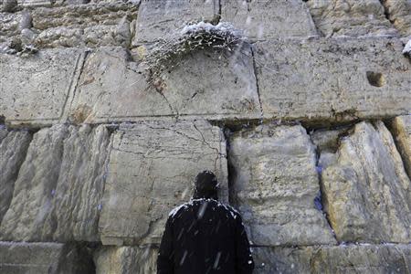 An Ultra-Orthodox Jewish man prays at the Western Wall in Jerusalem's Old City during a snowstorm December 13, 2013. REUTERS/Darren Whiteside