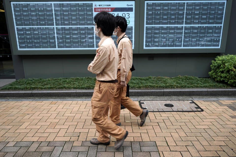 People walk past a blank electronic stock board supposedly showing Japan's Nikkei 225 index at a securities firm in Tokyo Thursday, Oct. 1, 2020. Trading on the Tokyo Stock Exchange was suspended Thursday because of a problem in the system for relaying market information. (AP Photo/Eugene Hoshiko)