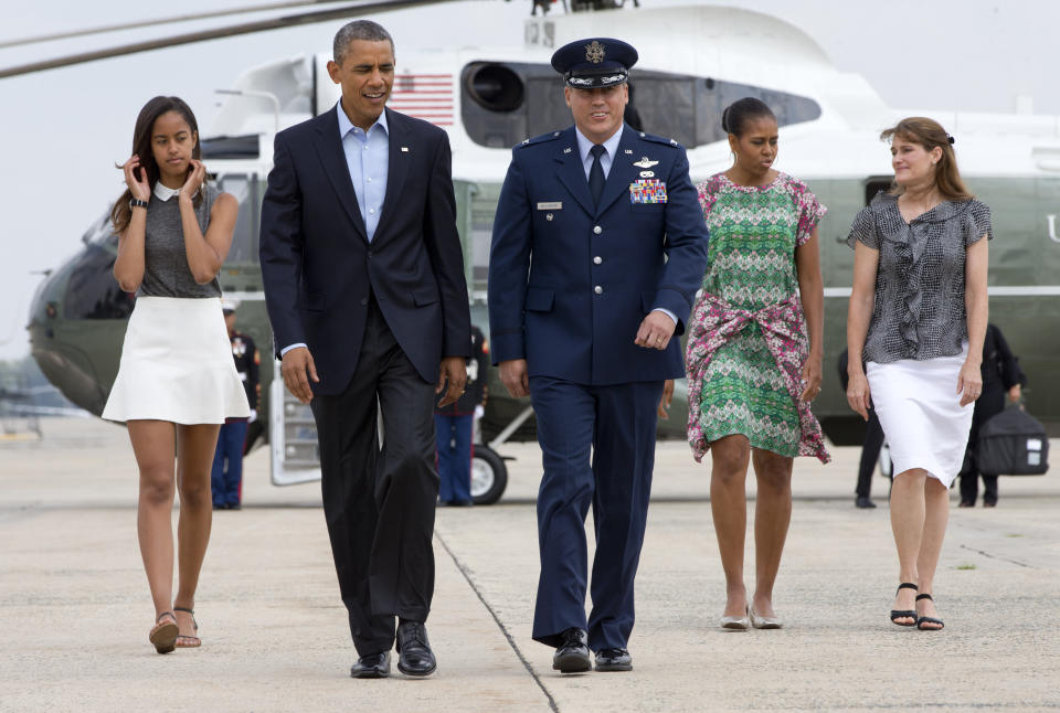 President Barack Obama walks from Marine One with Vice Commander of the 89th Airlift Wing at Andrew Air Force Base Col. Preston Williamson IV, followed by his daughter Malia Obama, first lady Michelle Obama and Christine Williamson, to board Air Force One at Andrews Air Force Base, Md., Saturday, Aug. 9, 2014. en route to a family vacation on the Massachusetts island of Martha's Vineyard. (AP Photo/Jacquelyn Martin)