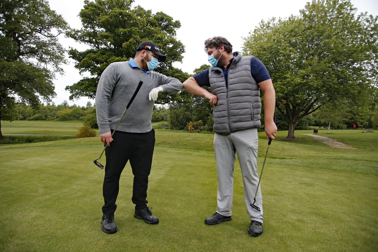 Golfers, wearing protective masks, bump elbows at Rookwood Golf Club, Horsham, Sussex, after golfers return to play as restrictions are lifted in England, as the UK continues in lockdown to curb the spread of coronavirus during the pandemic.