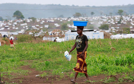 A Congolese woman, who fled ethnic fighting in the Democratic Republic of Congo on a fishing boat, across Lake Albert, carries belongings on her head at a United Nations High Commission for Refugees (UNHCR) settlement camp in Kyangwali, Uganda March 20, 2018. REUTERS/James Akena