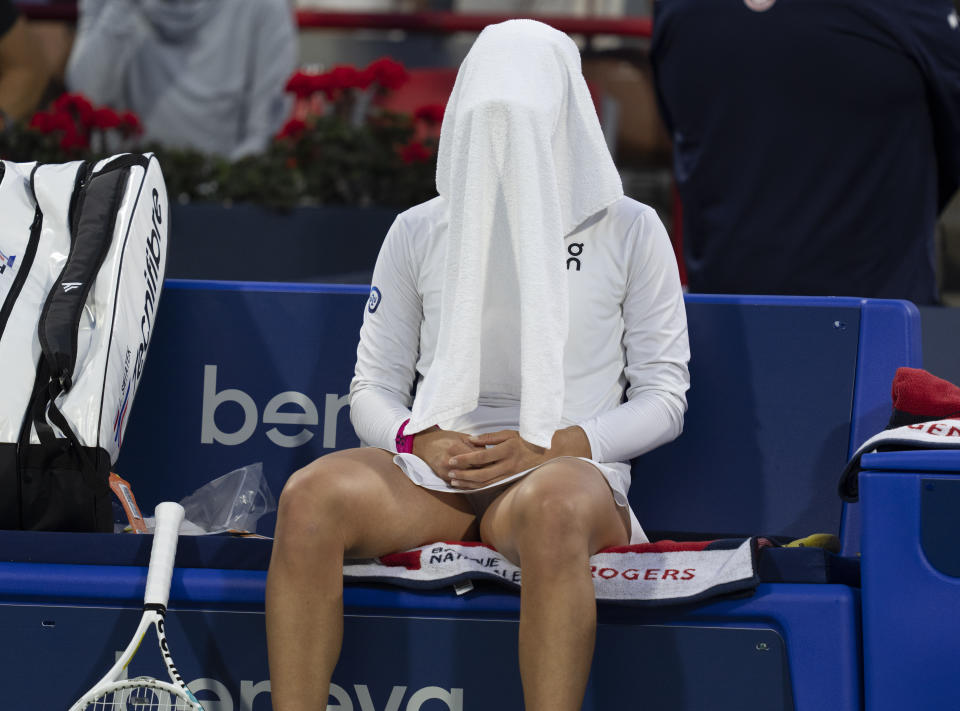 Iga Swiatek, of Poland, sits on the bench with a towel over her head during a changeover in a match against Danielle Collins, of the United States, during the National Bank Open women’s tennis tournament Friday, Aug. 11, 2023, in Montreal. (Christinne Muschi/The Canadian Press via AP)