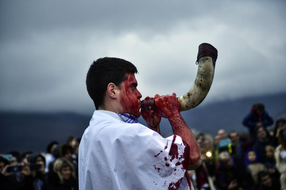 ââMomotxorroââ with his face covered with blood blood plays a horn while taking part in the carnival, in Alsasua, northern Spain, Tuesday, Feb. 25, 2020. During the carnival Momotxorros, characters who seem to have been resurrected from a prehistoric ritual, come out onto the streets wearing horns and hiding their faces under headscarves, and dressed in a white sheet stained with blood. (AP Photo/Alvaro Barrientos