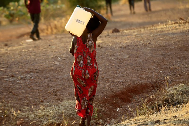 FILE PHOTO: An Ethiopian woman who fled war in Tigray region carries a jerrycan of water as she walks at the Um-Rakoba camp on the Sudan-Ethiopia border in Al-Qadarif state