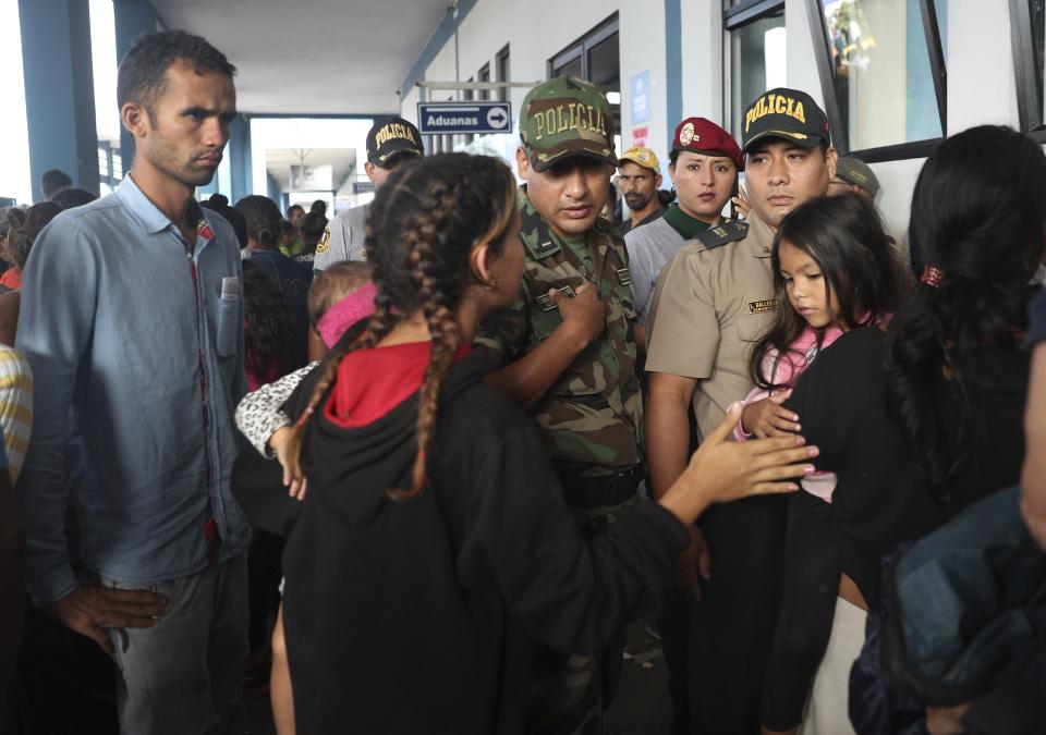 A police officer talks with Venezuelan migrants in the line of migrations office after stricter entry requirements went into effect, in Tumbes, Peru, Saturday, June 15, 2019. With its relatively stable economy and flexible immigration laws, Peru has become a main destination for millions of Venezuelans escaping hyperinflation, medical shortages and political repression at home. (AP Photo/Martin Mejia)