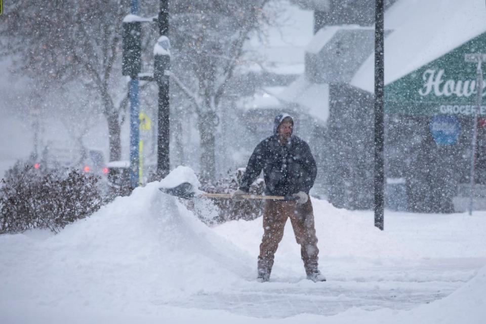 A man shovels a sidewalk during a period of heavy snowfall in Surrey, British Columbia on Wednesday, January 17, 2024. 