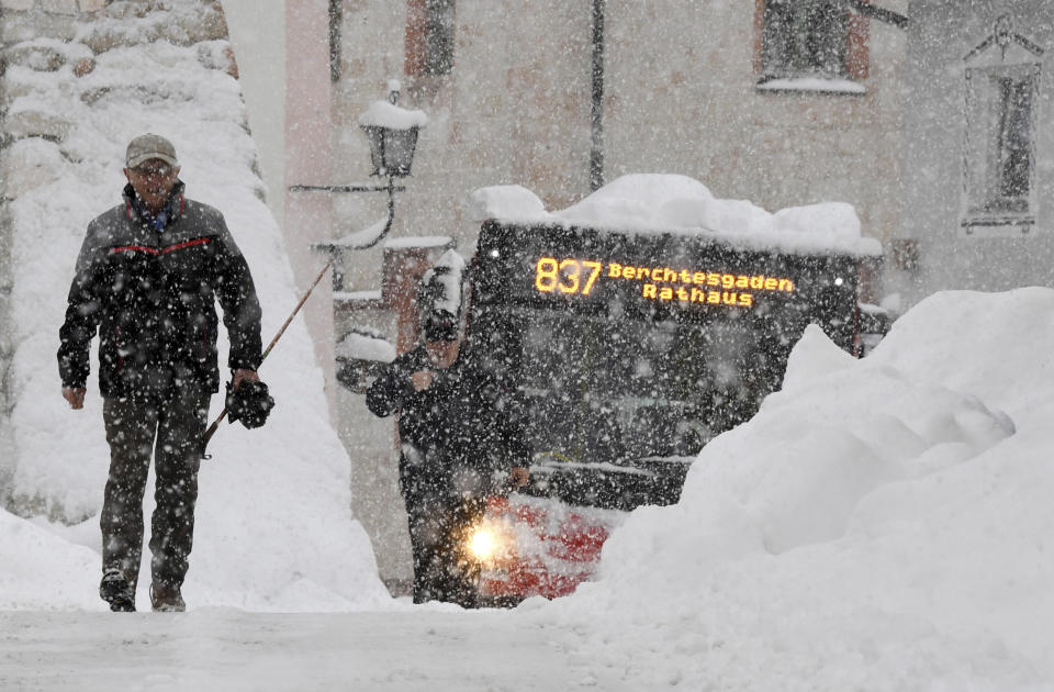 A man and a bus make their way on a street in Berchtesgaden, southern Germany, Thursday, Jan. 10, 2019 after large parts of southern Germany and Austria were hit by heavy snowfall. (Tobias Hase/dpa via AP)