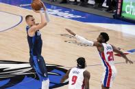 Dallas Mavericks center Kristaps Porzingis shoots as Detroit Pistons' Jerami Grant (9) and Josh Jackson (20) defend during the first half of an NBA basketball game in Dallas, Wednesday, April 21, 2021. (AP Photo/Tony Gutierrez)