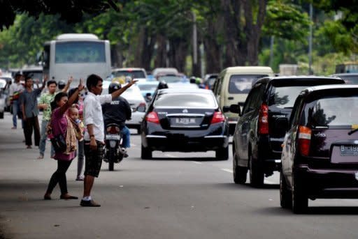 Traffic jockeys gesture to motorists on a busy street in Jakarta. The jockeys know they are violating the law and could be fined or detained for several weeks if caught. But for the most part police turn a blind eye to the hundreds on the streets each day