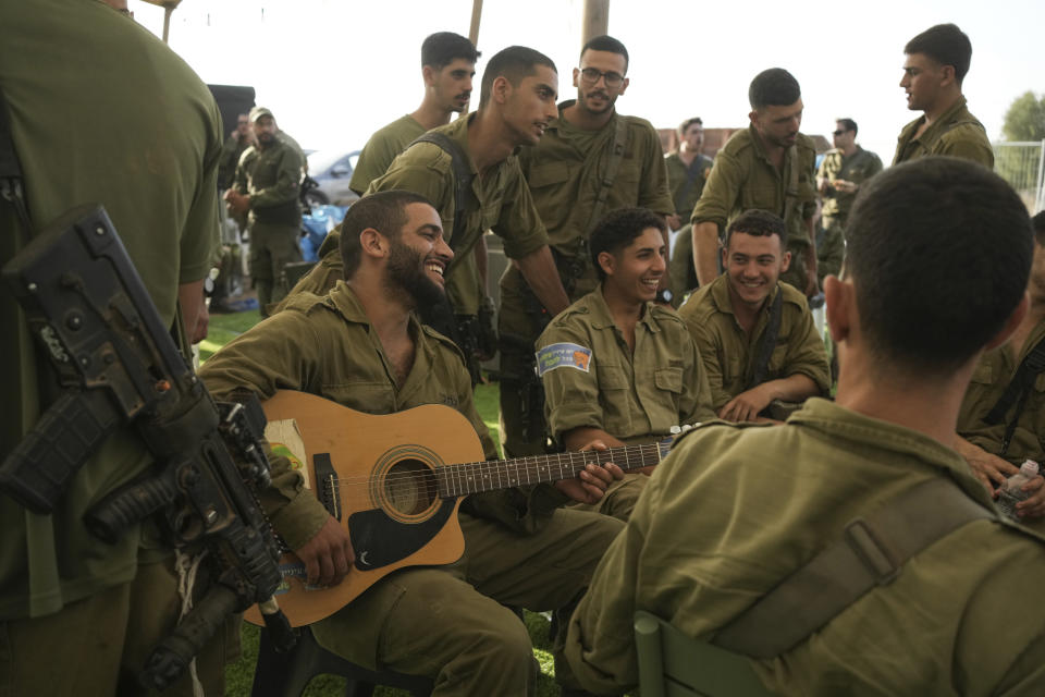 An Israeli soldier plays the guitar at a staging area near the border with the Gaza Strip, in southern Israel Monday, Oct. 23, 2023. (AP Photo/Maya Alleruzzo)