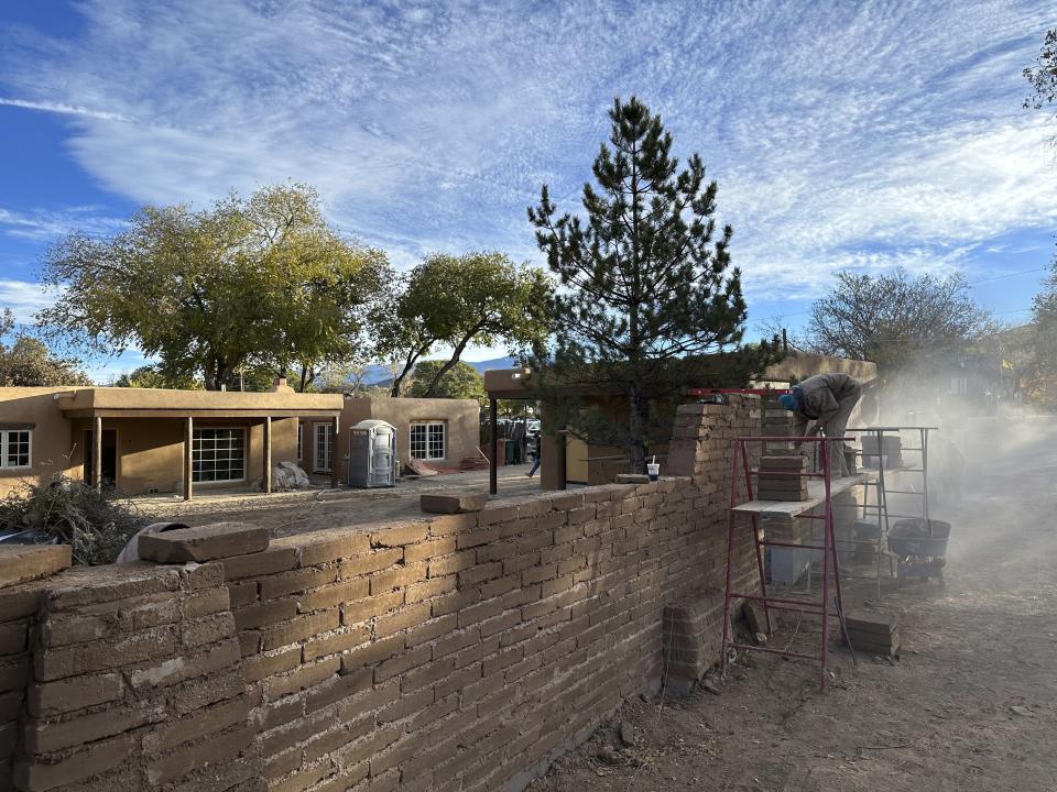 A mason works on an adobe-brick wall along a residential lane lined with multimillion-dollar homes in Santa Fe, N.M., on Friday, Nov. 3, 2023. Voters are deciding whether to tax mansions to pay for affordable housing initiatives in a state capital city prized for its desert-mountain vistas, vibrant arts scene and stucco architecture rooted in Native American and Spanish-colonial tradition. (AP Photo/Morgan Lee)