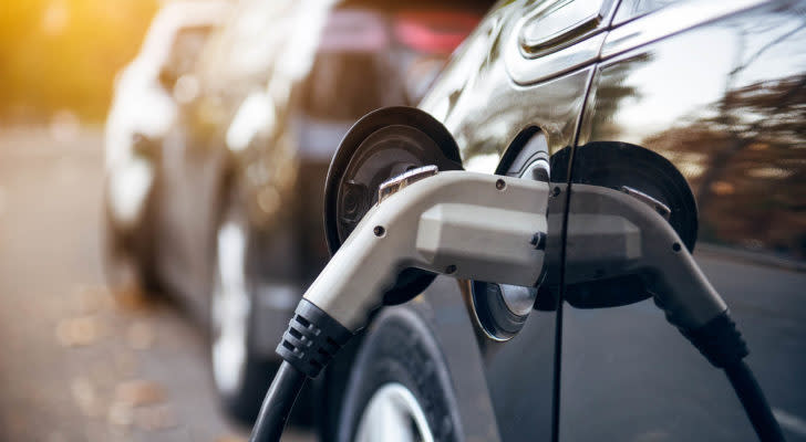 A photo of an electric car with the charger plugged in.