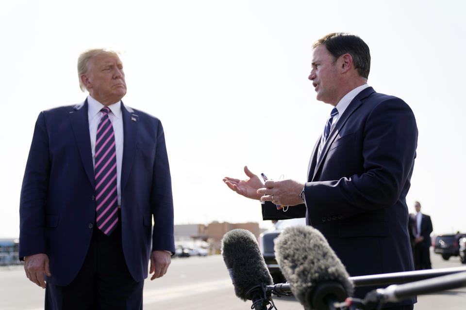 In this Sept. 14, 2020 file photo, President Donald Trump listens as Arizona Gov. Doug Ducey speaks at Phoenix Sky Harbor International Airport in Phoenix. Ducey spent much of Trump's presidency trying not to provoke confrontation with the president or his fervent defenders. When state law required Ducey to certify Arizona's presidential election results and sign off on Trump's defeat last week, four years of loyalty wasn't enough to protect him from the president. (AP Photo/Andrew Harnik, File)