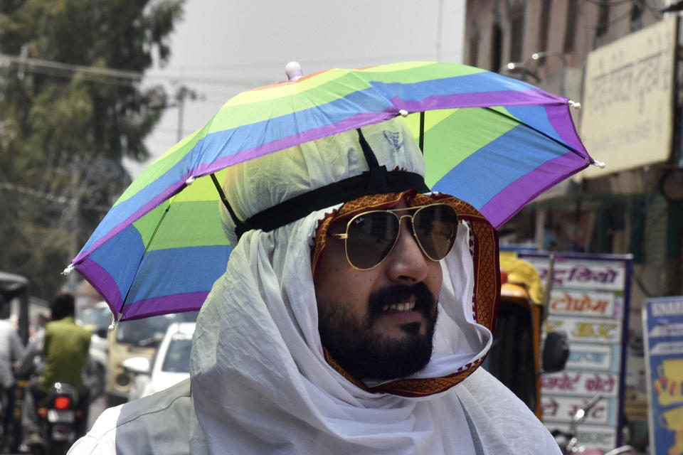 A man wears an umbrella hat on a hot summer day in Bikaner, in the Indian western state of Rajasthan, Thursday, May 23, 2024. (AP Photo/Dinesh Gupta)