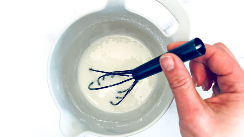 hand stirring white frosting