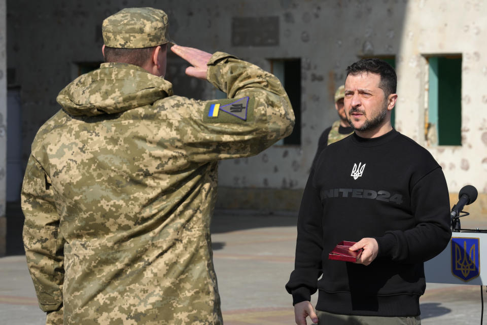 A serviceman salutes Ukrainian President Volodymyr Zelenskyy as he is awarded a medal in Trostianets in the Sumy region of Ukraine, Tuesday March 28, 2023. (AP Photo/Efrem Lukatsky)