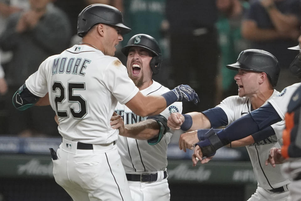 Seattle Mariners' Dylan Moore (25) is greeted by Tom Murphy, center, and Jarred Kelenic, right, after Moore hit a grand slam during the eighth inning of a baseball game against the Houston Astros, Monday, July 26, 2021, in Seattle. (AP Photo/Ted S. Warren)