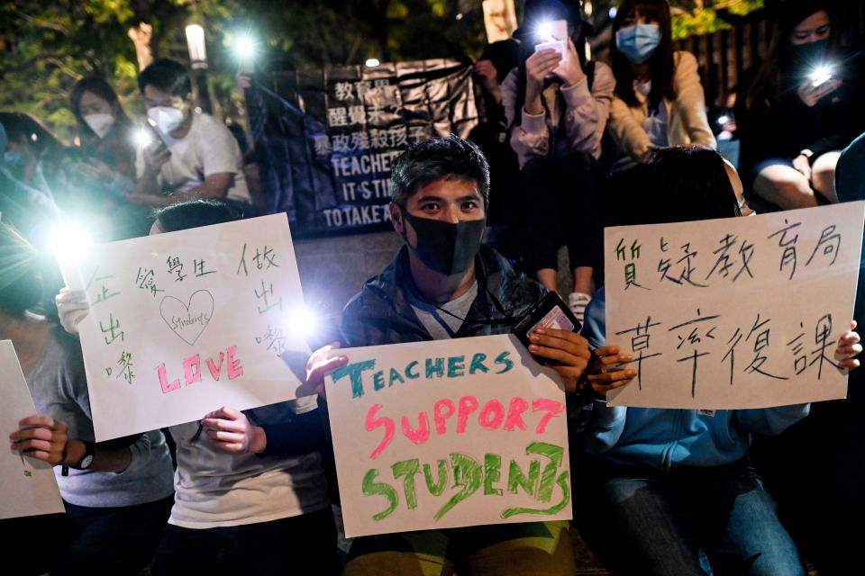 People hold placards and mobile phones as they gather to pray for the students who are barricaded inside Hong Kong Polytechnic University at Salisbury garden in Tsim Sha Tsui district of Hong Kong on November 19, 2019. - A dwindling number of exhausted pro-democracy protesters barricaded inside the Hong Kong university defied warnings on November 19 to surrender, as a police siege of the campus stretched through a third day and China sent fresh signals that its patience with nearly six months of unrest was running out. (Photo by YE AUNG THU / AFP) (Photo by YE AUNG THU/AFP via Getty Images)