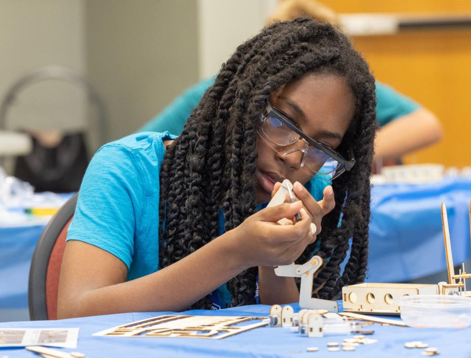 Twelve-year-old Colette Snell works on construting a hydraulic arm model on Tuesday during the NASA Astro Camp at the Massillon Recreation Center.